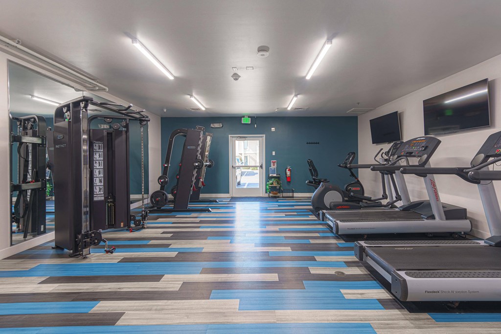 a gym with cardio machines and weights on a checkered floor